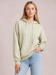 A model poses in a relaxed, pale green checkered hoodie shirt with a drawstring hood, long sleeves, and a loose silhouette.