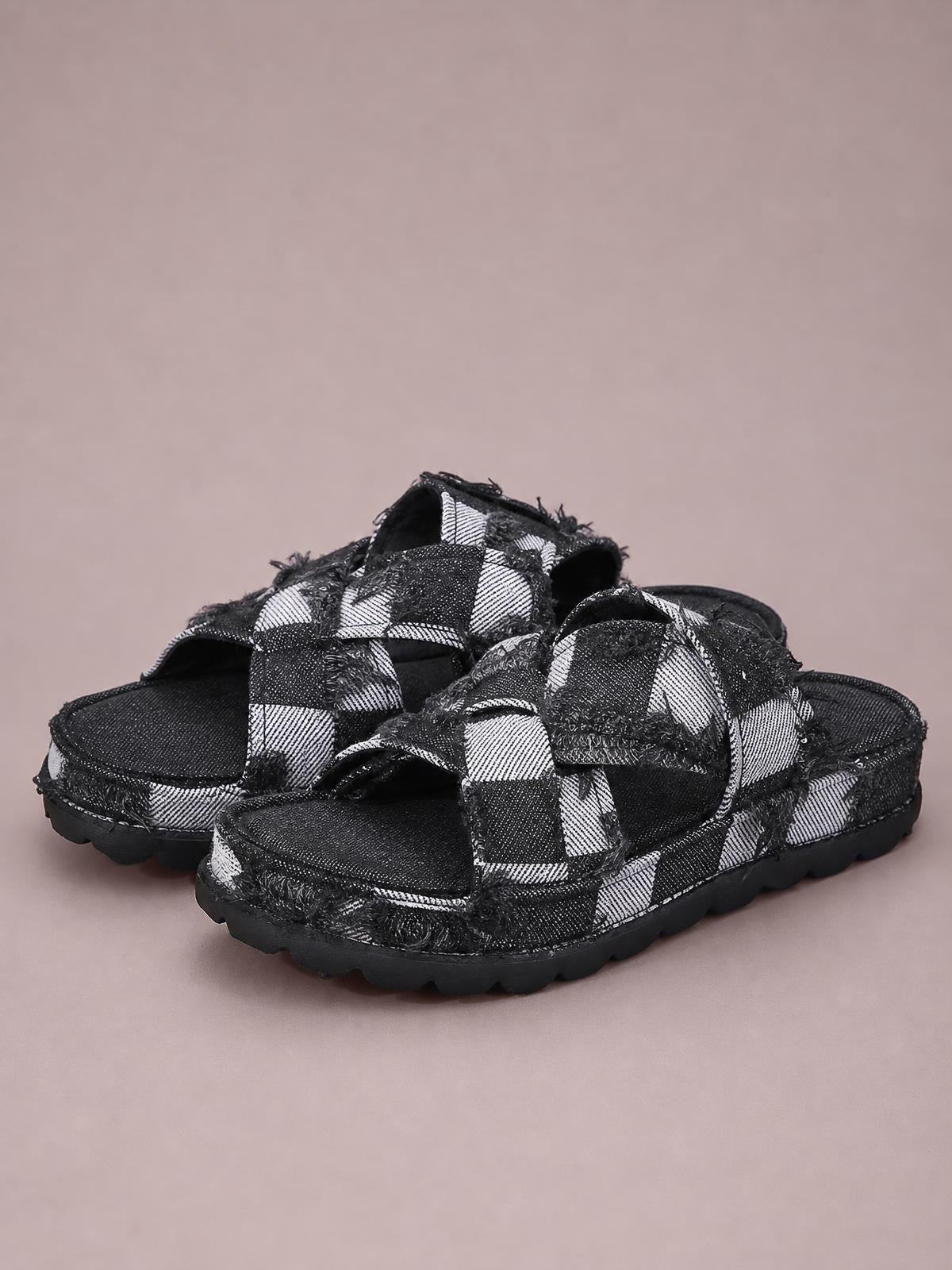 Black-and-white checkered canvas sandals feature open toes, wide crisscross straps, raw frayed hems, and chunky flat rubber platform soles.