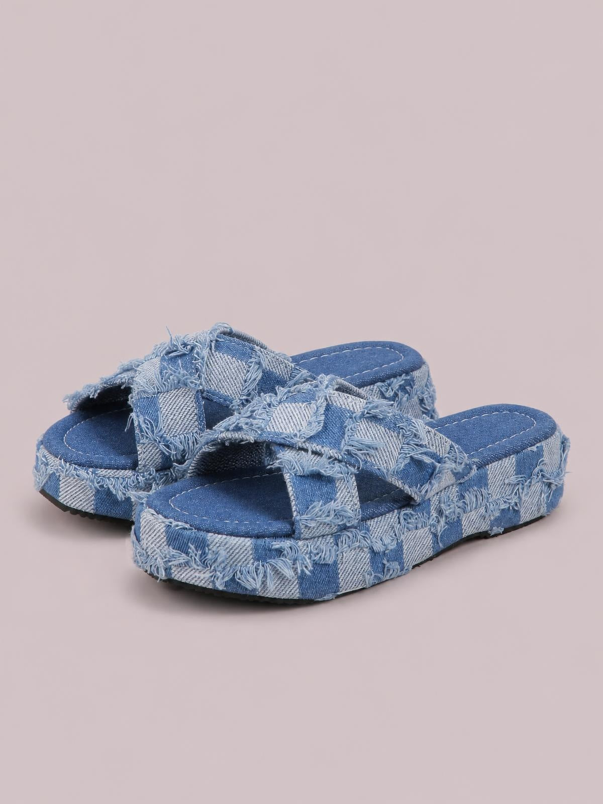 Blue checkered canvas platform sandals feature open toes, wide crisscross straps, frayed raw hems, and sturdy rubber soles.