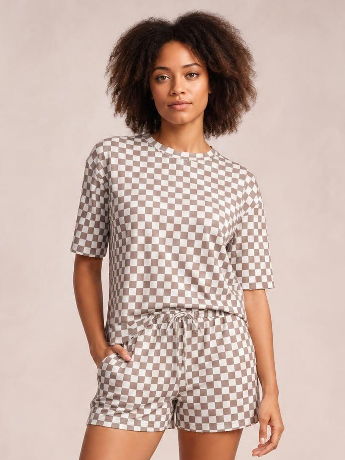 Model wearing a brown and white checkered round neck top and drawstring shorts set, featuring a relaxed silhouette, short sleeves, and side pockets.