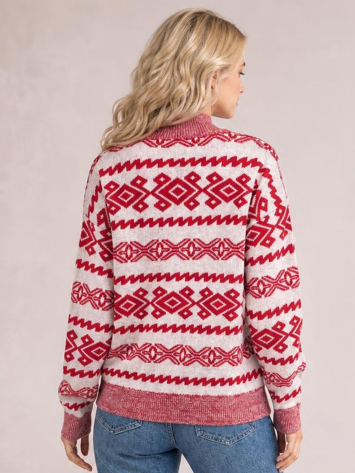 A model shows the back of a red and white Christmas long-sleeve sweater with geometric patterned bands, ribbed cuffs and hem, and a relaxed silhouette.