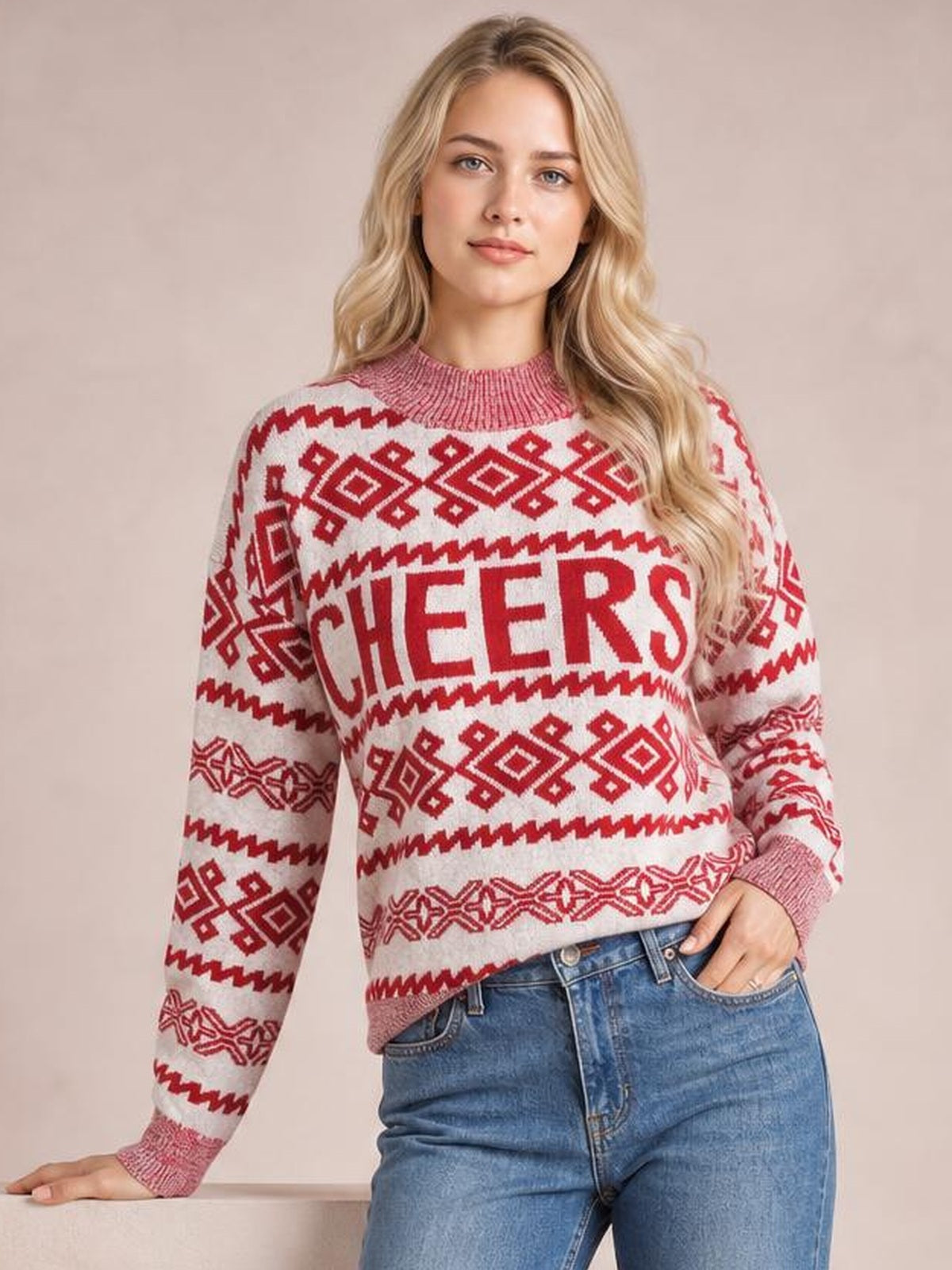 A model poses in a cream and red Christmas sweater with a ribbed round neck, long sleeves, geometric motifs, and bold CHEERS lettering.