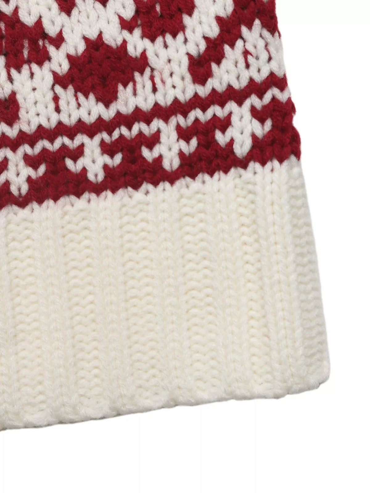 Close-up of a cream Christmas cable knit sweater with red festive patterned bands, textured vertical ribbing, and a softly curved hem.