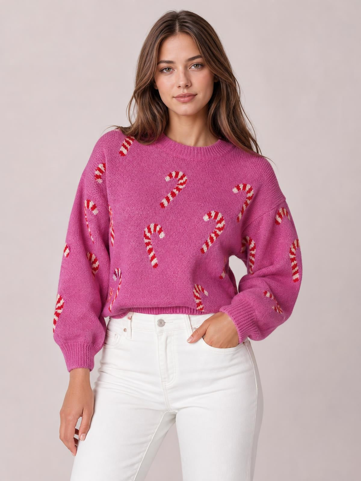 Model poses in a pink Christmas candy cane sweater with a drop-shoulder silhouette, crew neck, relaxed fit, and ribbed cuffs and hem.