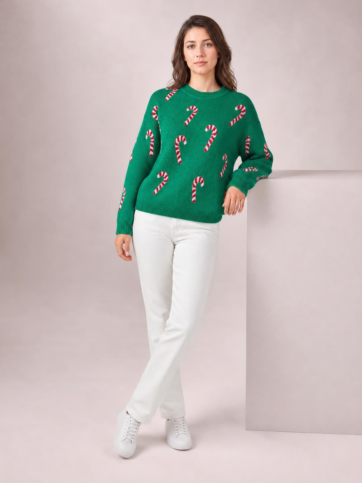 Model poses in a green Christmas sweater with red-and-white candy cane motifs, ribbed crew neck and cuffs, drop shoulders, and a relaxed silhouette.