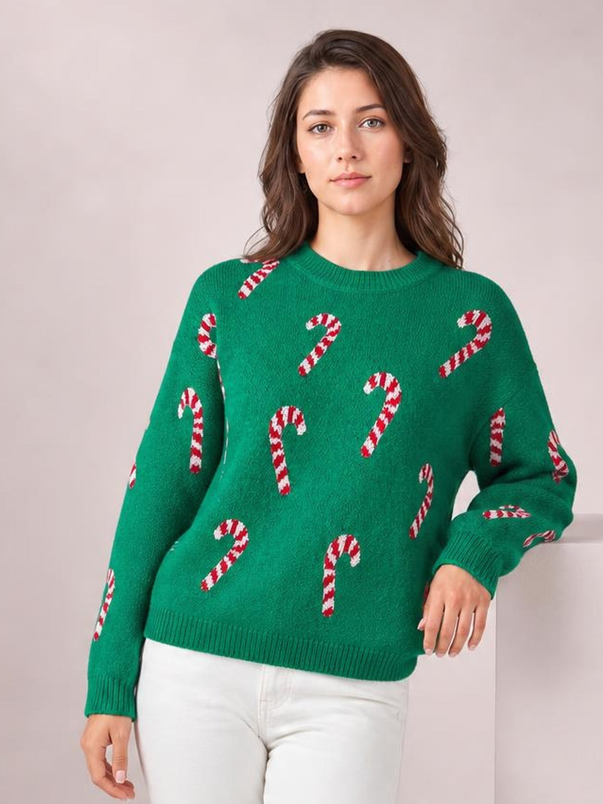 Model wears a green ribbed Christmas sweater with red-and-white candy cane motifs, drop shoulders, crew neck, ribbed cuffs and hem.