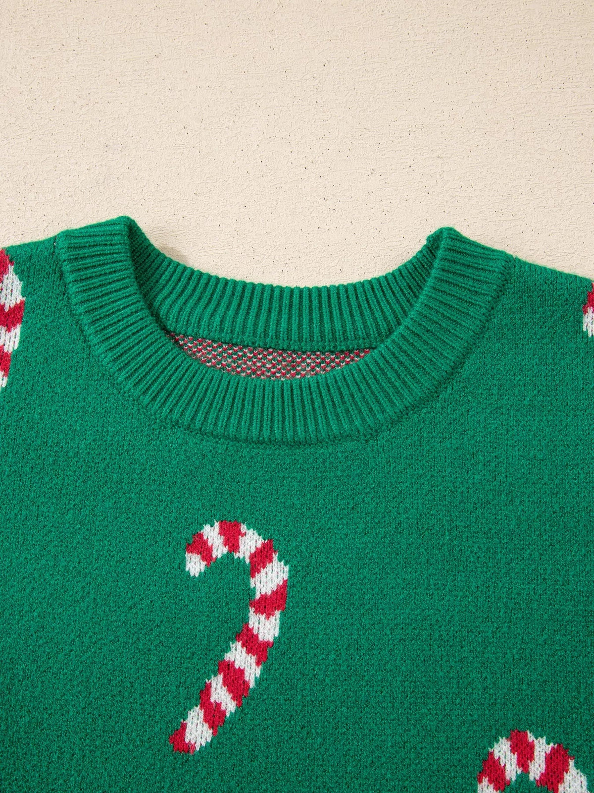 A green ribbed holiday sweater features a crew neckline with contrasting knit trim and red-and-white candy cane motifs.