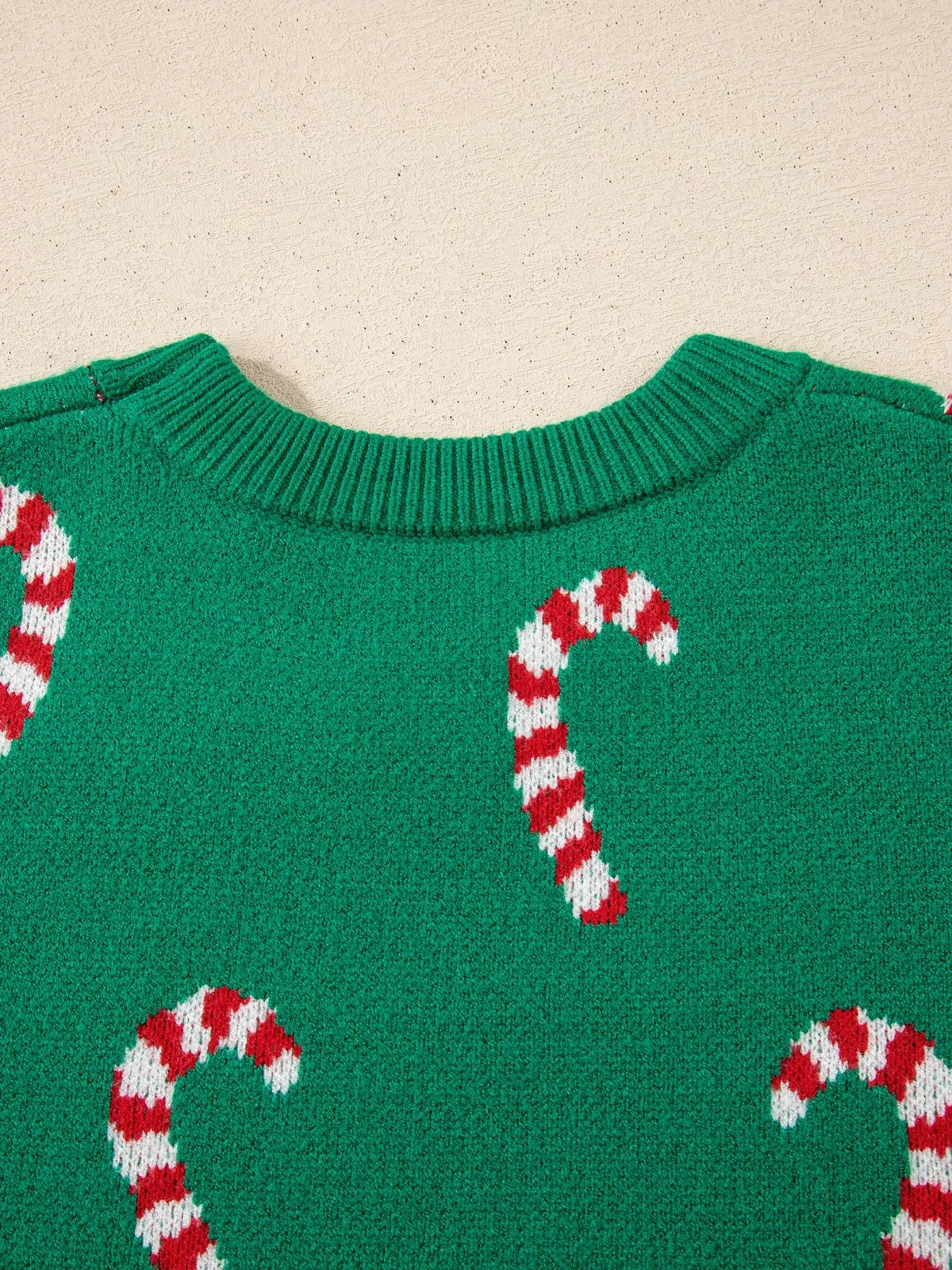 Green ribbed Christmas sweater featuring a crew neckline and repeating red-and-white candy cane pattern knit across the front.