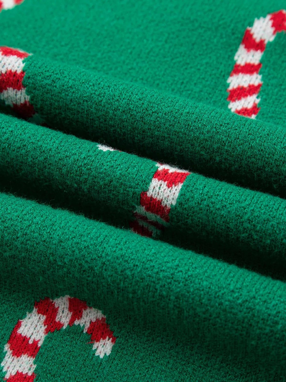 Close-up of a green ribbed Christmas sweater featuring red-and-white candy cane stripes in a soft, textured knit.