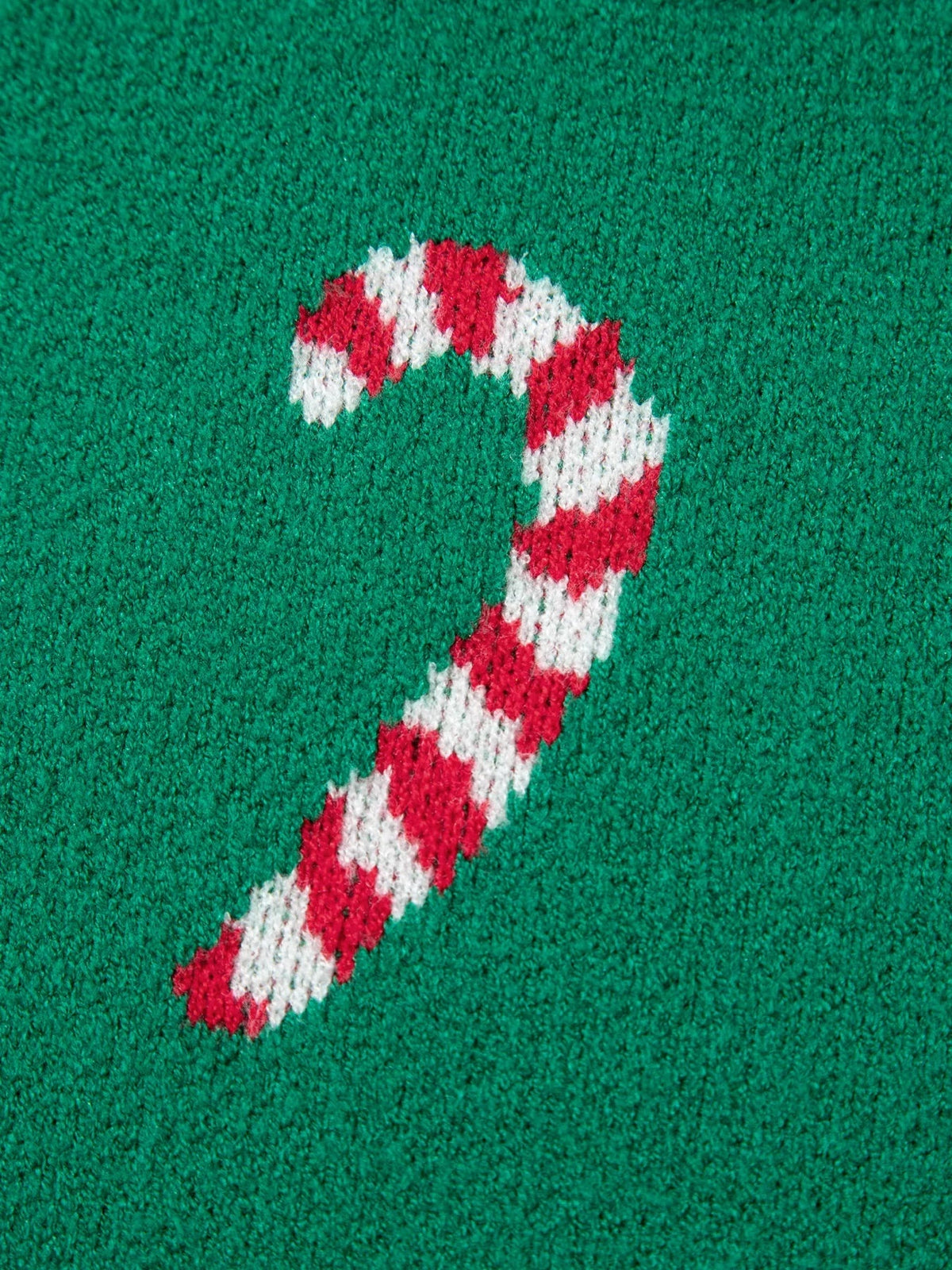 Close-up of a green ribbed knit Christmas sweater featuring a red-and-white candy cane motif in a textured stitch.