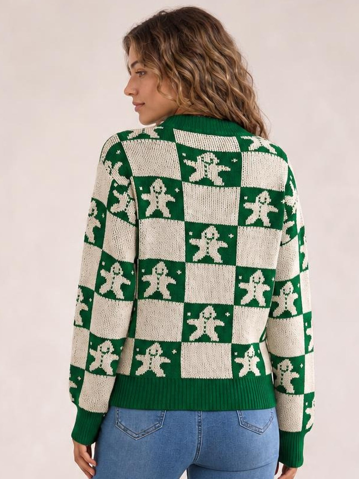 A model poses from the back in a green and cream Christmas checkerboard sweater with gingerbread motifs, round neck, long sleeves, and ribbed cuffs and hem.