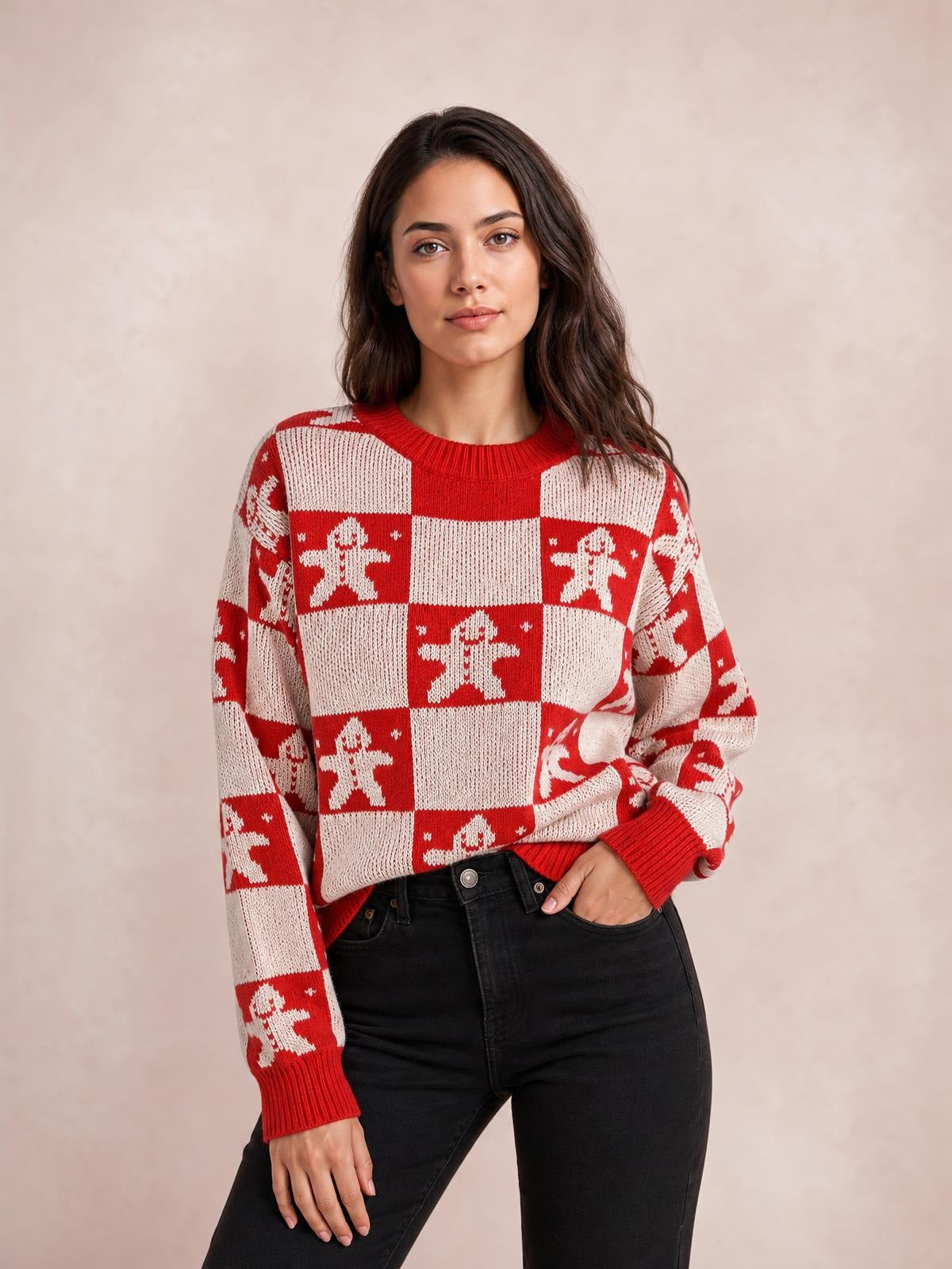 Model poses in a red and cream Christmas checkerboard gingerbread sweater with a round neck, long sleeves, ribbed cuffs and hem, and a relaxed silhouette.