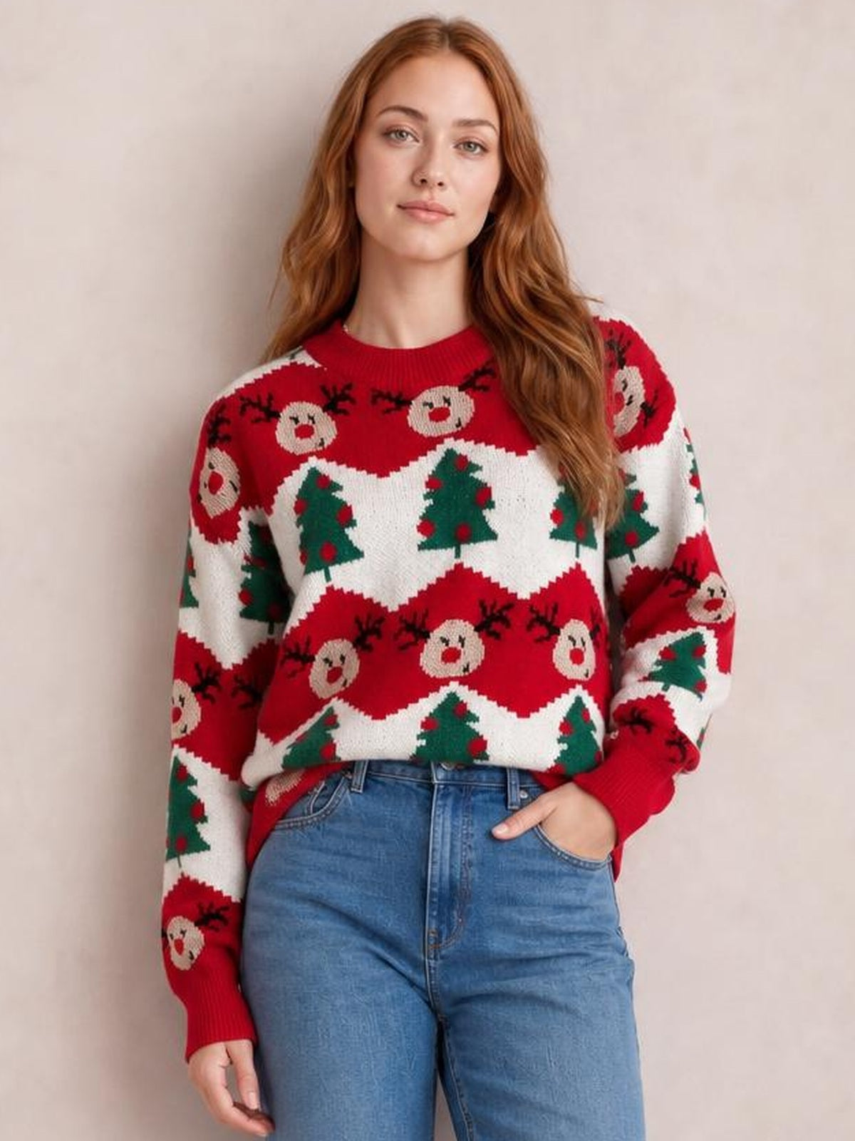 Model wearing a red Christmas sweater with a round neck, long sleeves, ribbed cuffs, and festive reindeer and Christmas tree patterns in a relaxed silhouette.