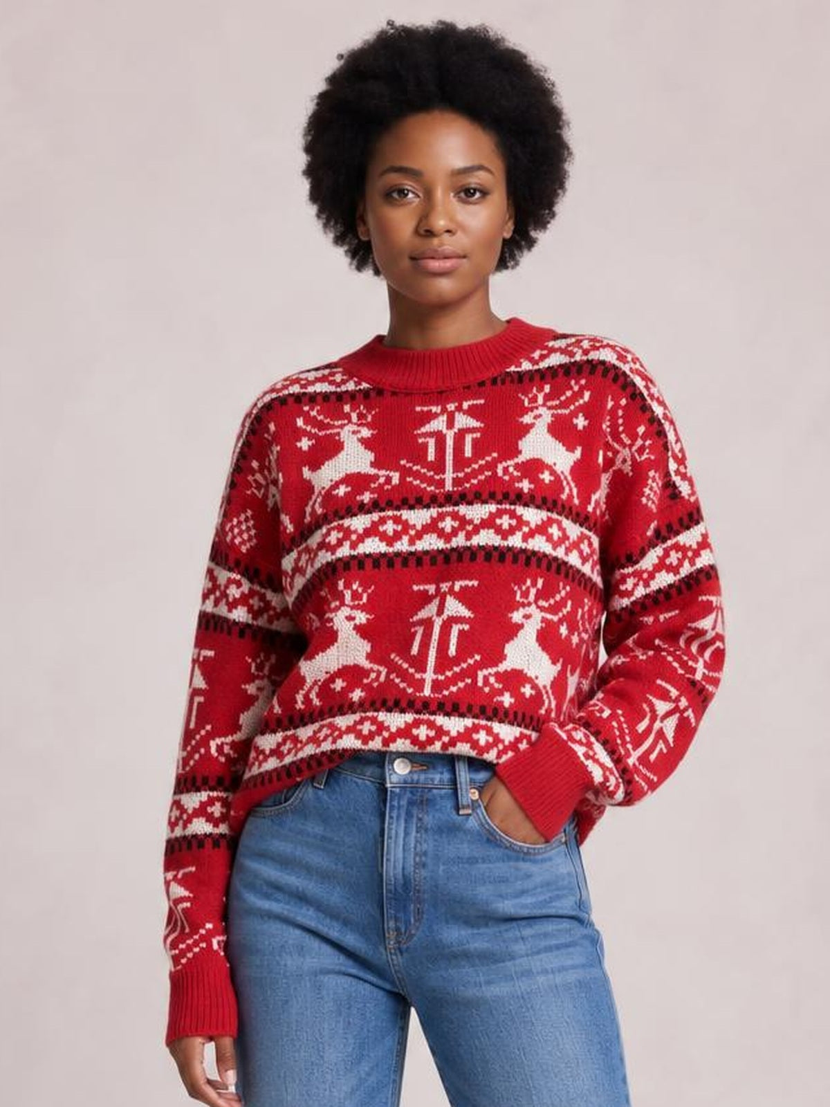 Model wears a red Christmas sweater with a round ribbed neck, long sleeves, festive reindeer and snowflake knit pattern, and a relaxed silhouette.