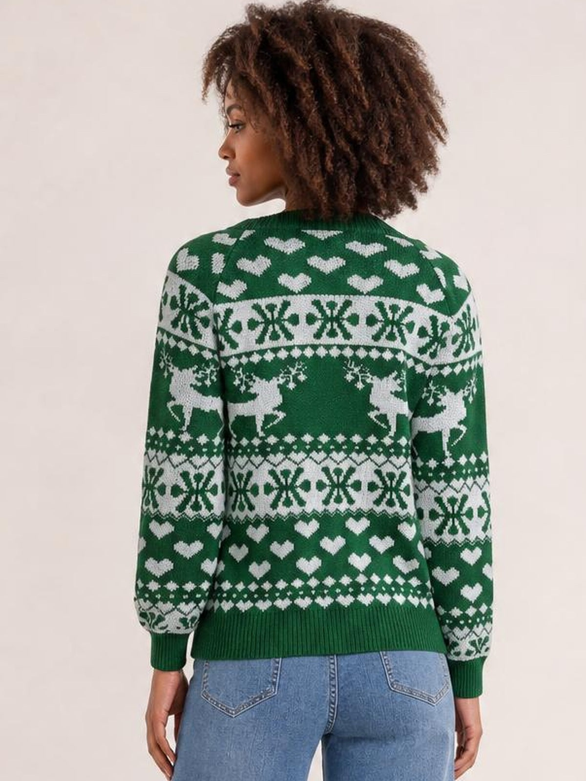 Model shown from the back wears a green Christmas round-neck long-sleeve sweater with white hearts, reindeer, snowflakes, and ribbed cuffs and hem.