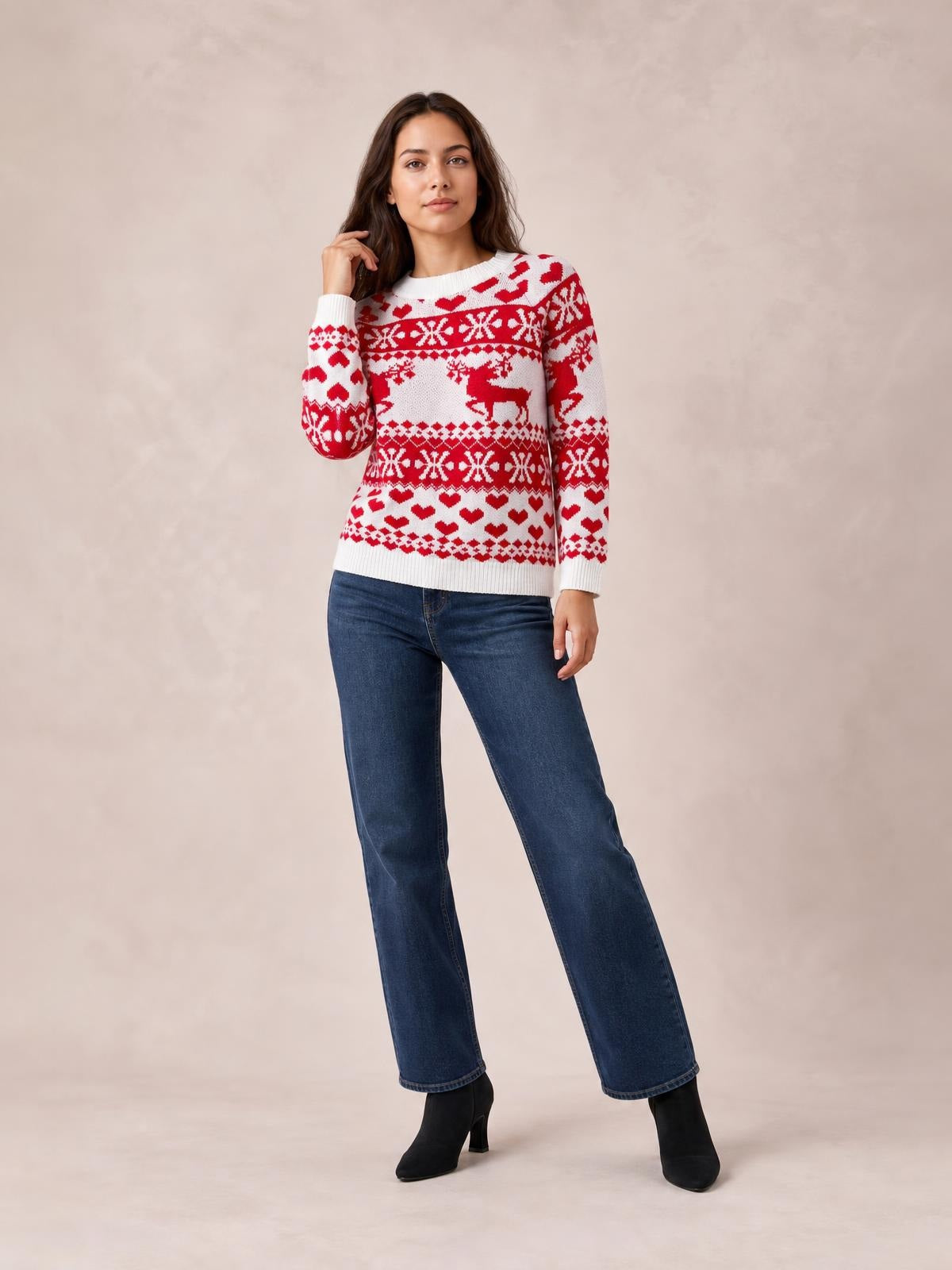 Model poses in a white Christmas sweater with red reindeer, hearts, and snowflake patterns, featuring a round neck, long sleeves, and a relaxed silhouette.