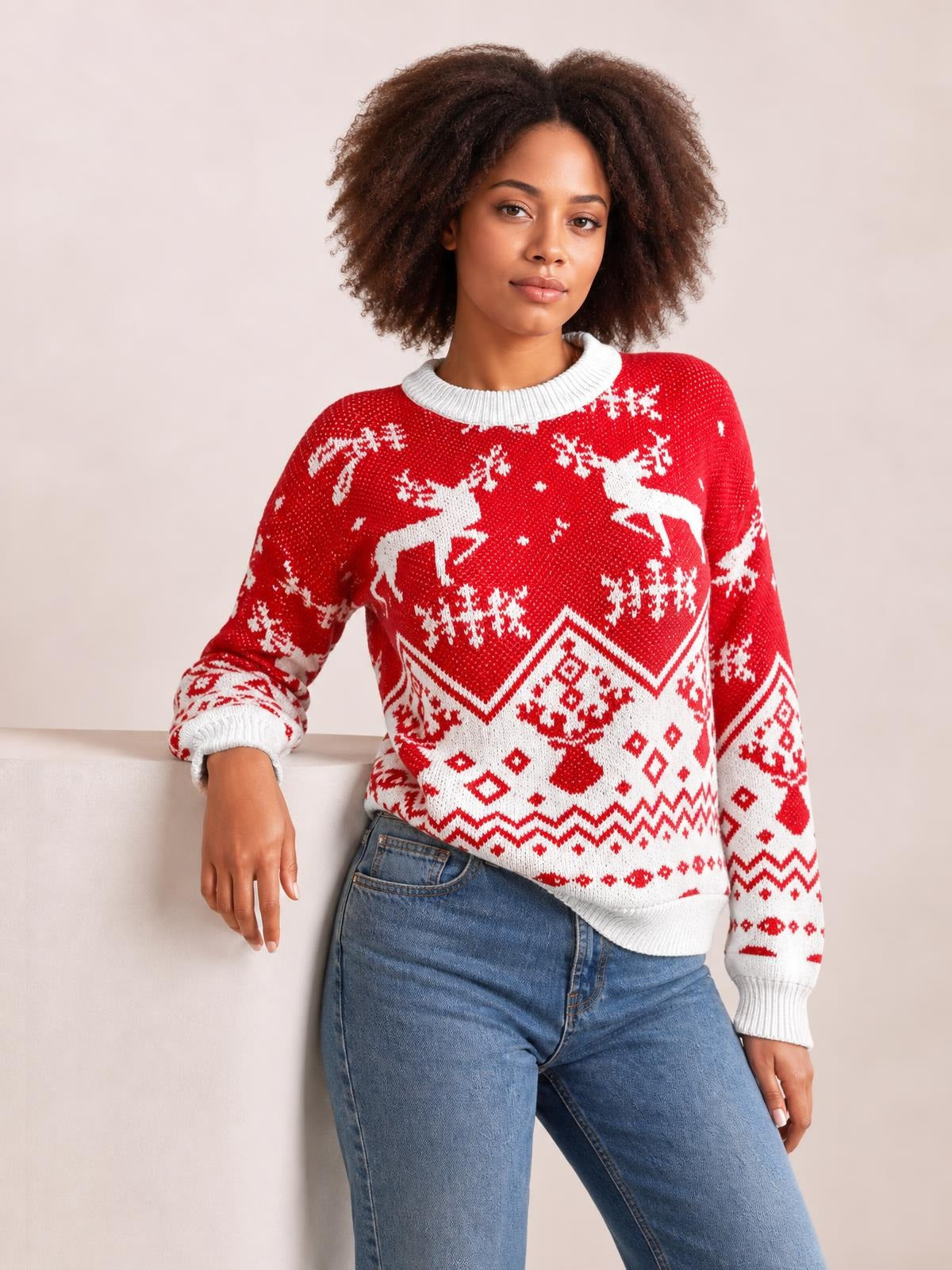 Model wears a red Christmas sweater with white reindeer and snowflake motifs, a ribbed round neck, long sleeves, and a relaxed silhouette.
