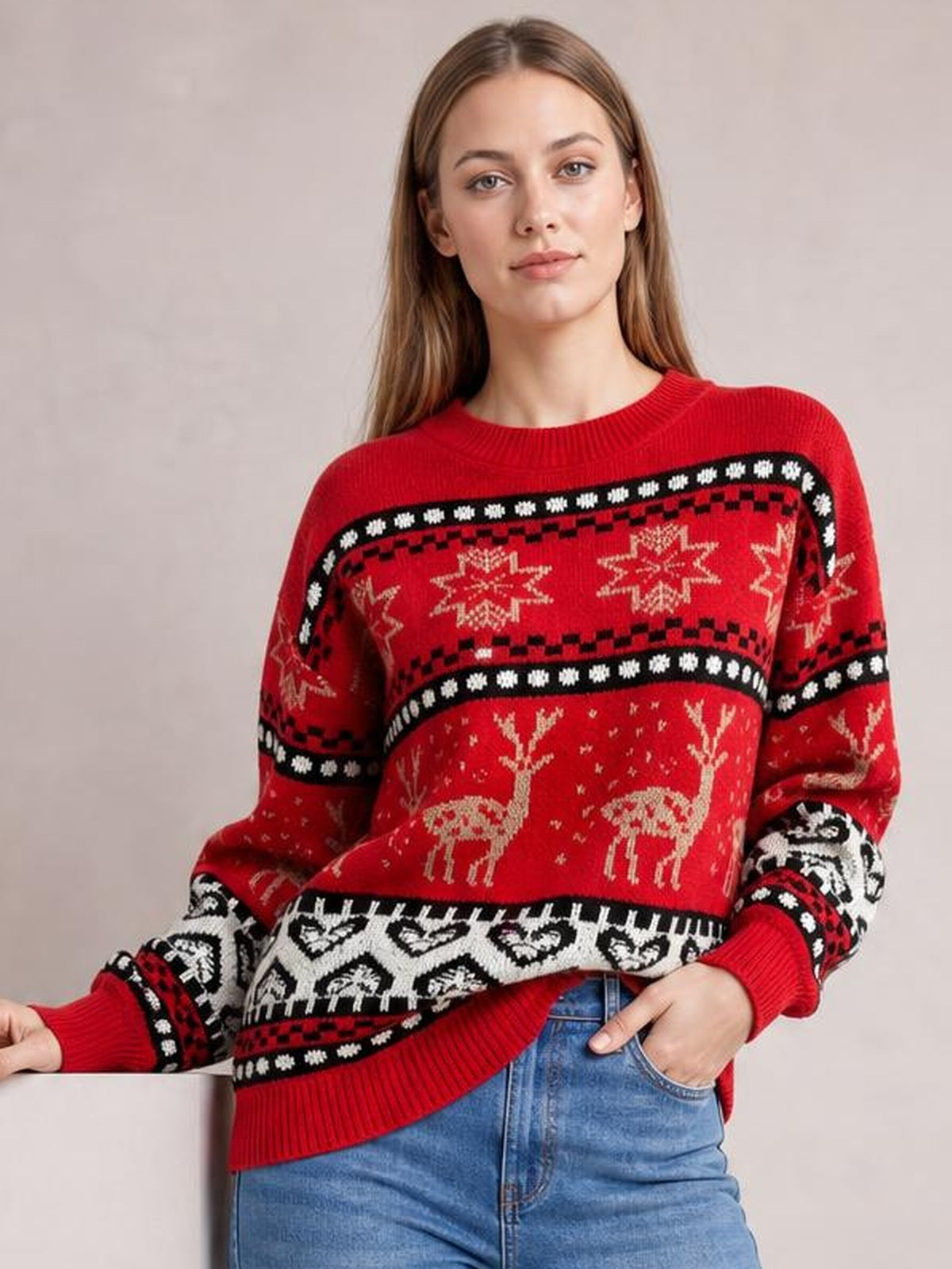 Model poses in a red Christmas sweater with a round neck, long sleeves, relaxed silhouette, ribbed trims, and festive reindeer and snowflake patterns.