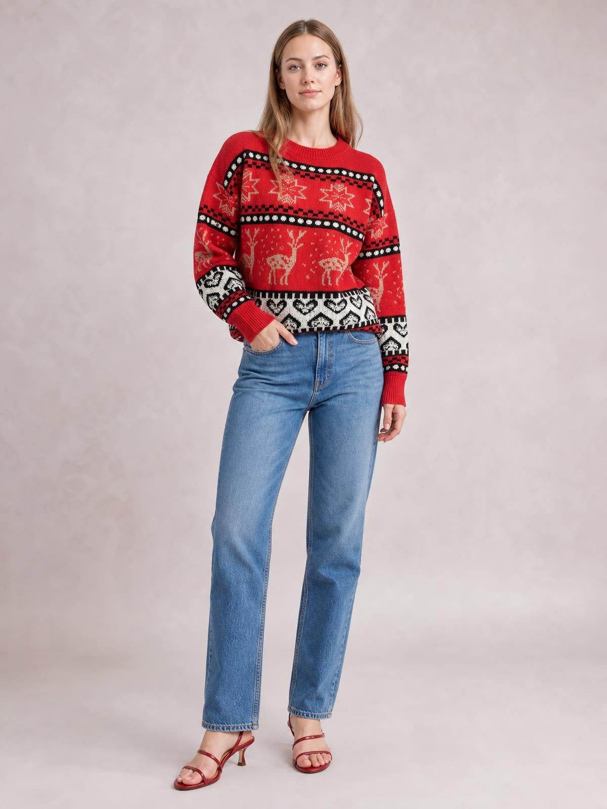 Model poses in a red Christmas element round-neck long-sleeve sweater with festive reindeer, star, and geometric knit patterns in a relaxed silhouette.