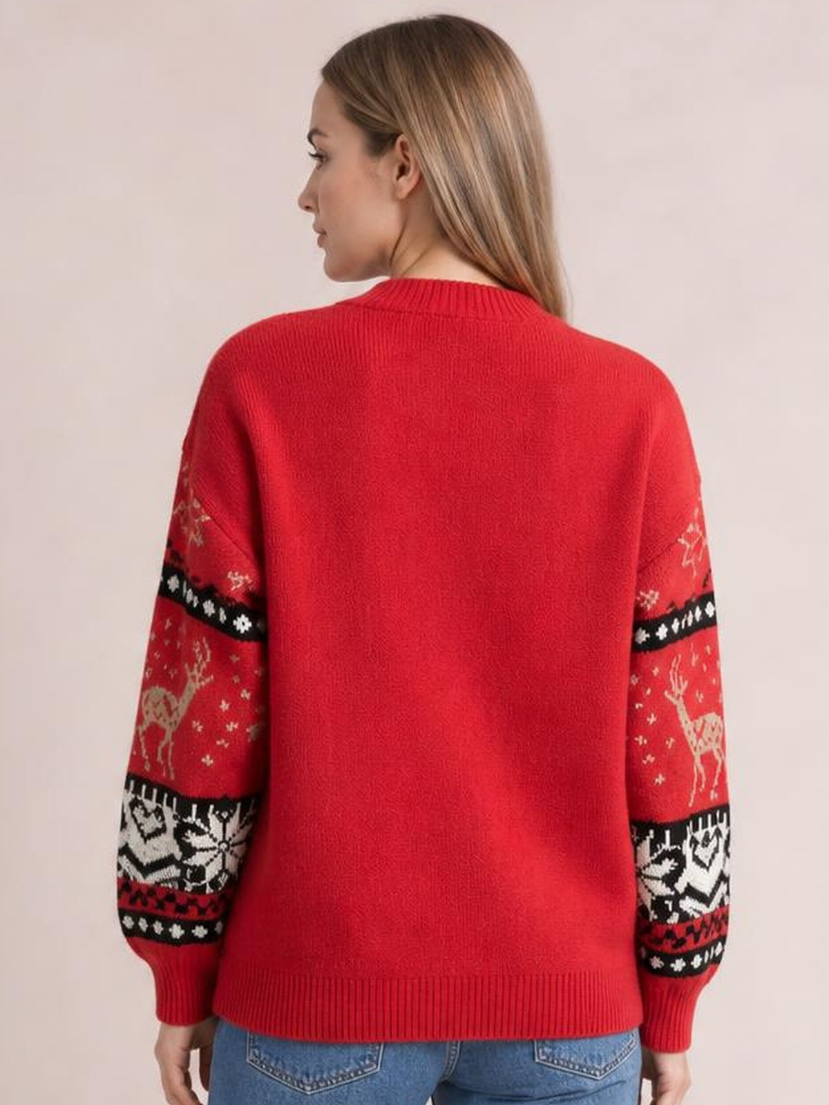 Model seen from behind wearing a red Christmas sweater with a round neck, long sleeves, ribbed trims, and festive reindeer and snowflake sleeve patterns.