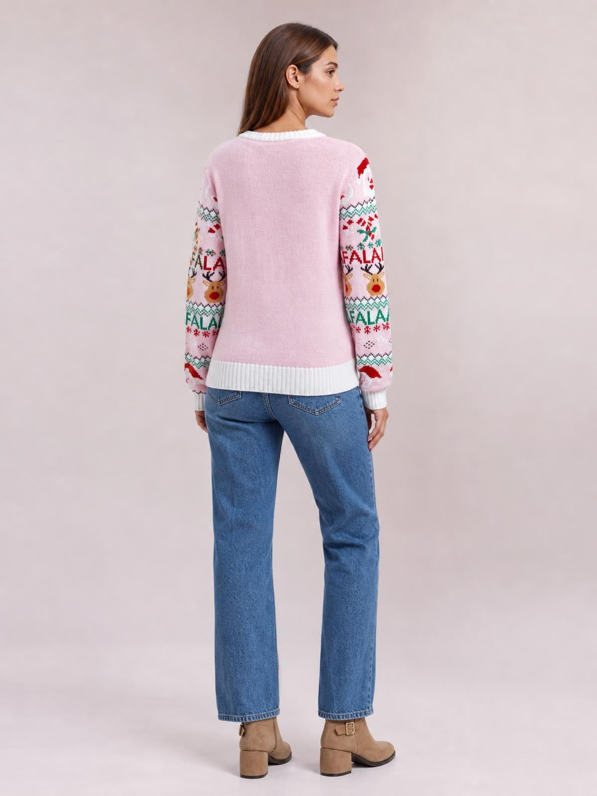 Model shown from the back wears a pink Christmas sweater with long patterned sleeves, a round neckline, white ribbed cuffs and hem, and a relaxed silhouette.
