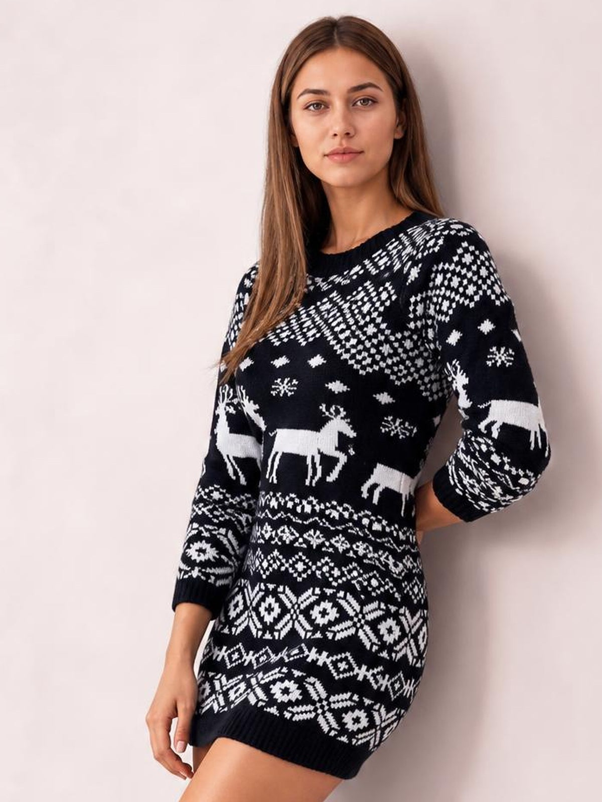Model wearing a black-and-white Christmas round-neck mini sweater dress with long sleeves, reindeer and snowflake patterns, a fitted silhouette, and ribbed hem.