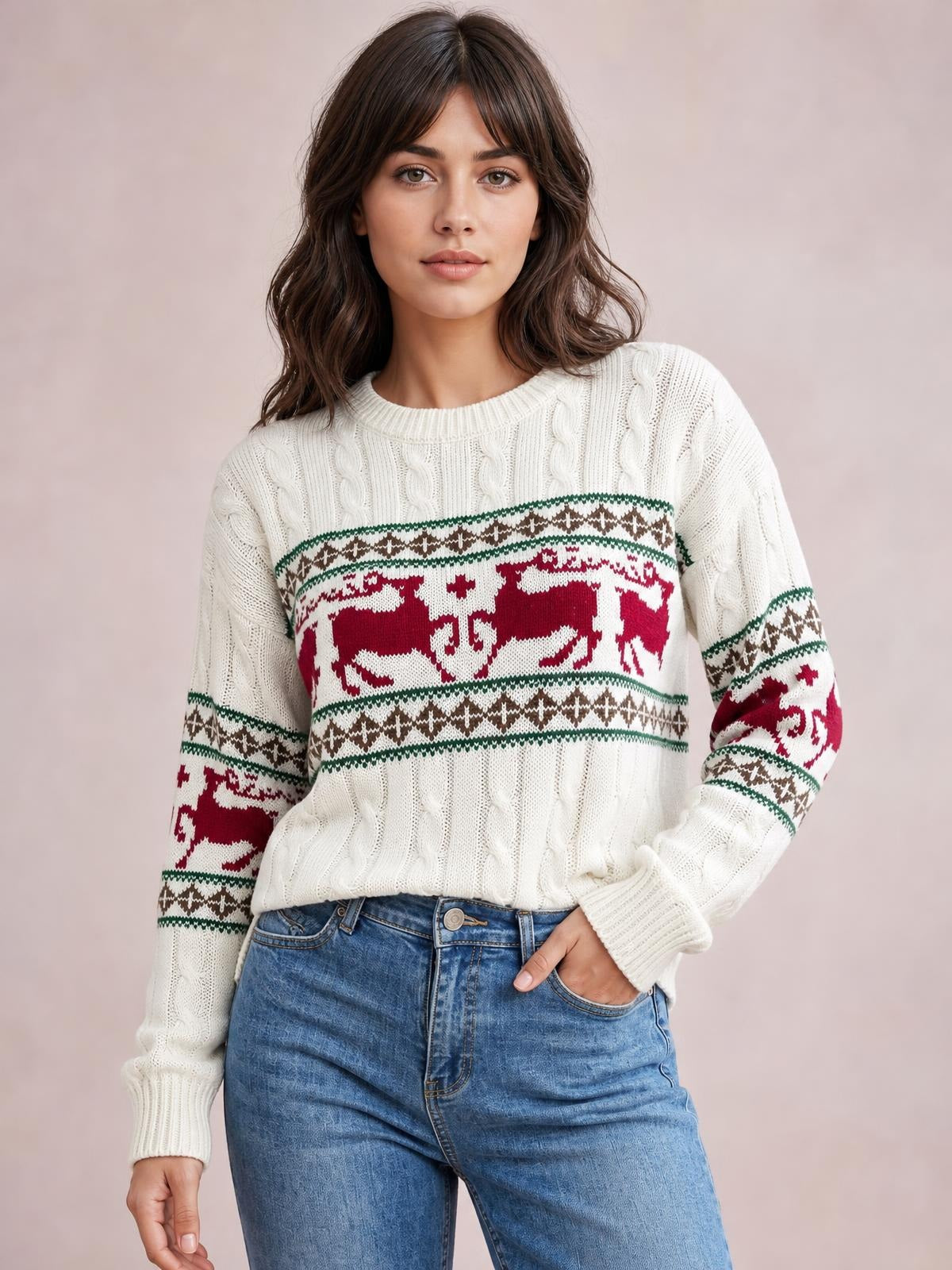 Model wearing a white cable-knit Christmas reindeer sweater with a relaxed silhouette, crew neckline, long sleeves, and red, green, and brown patterned bands.