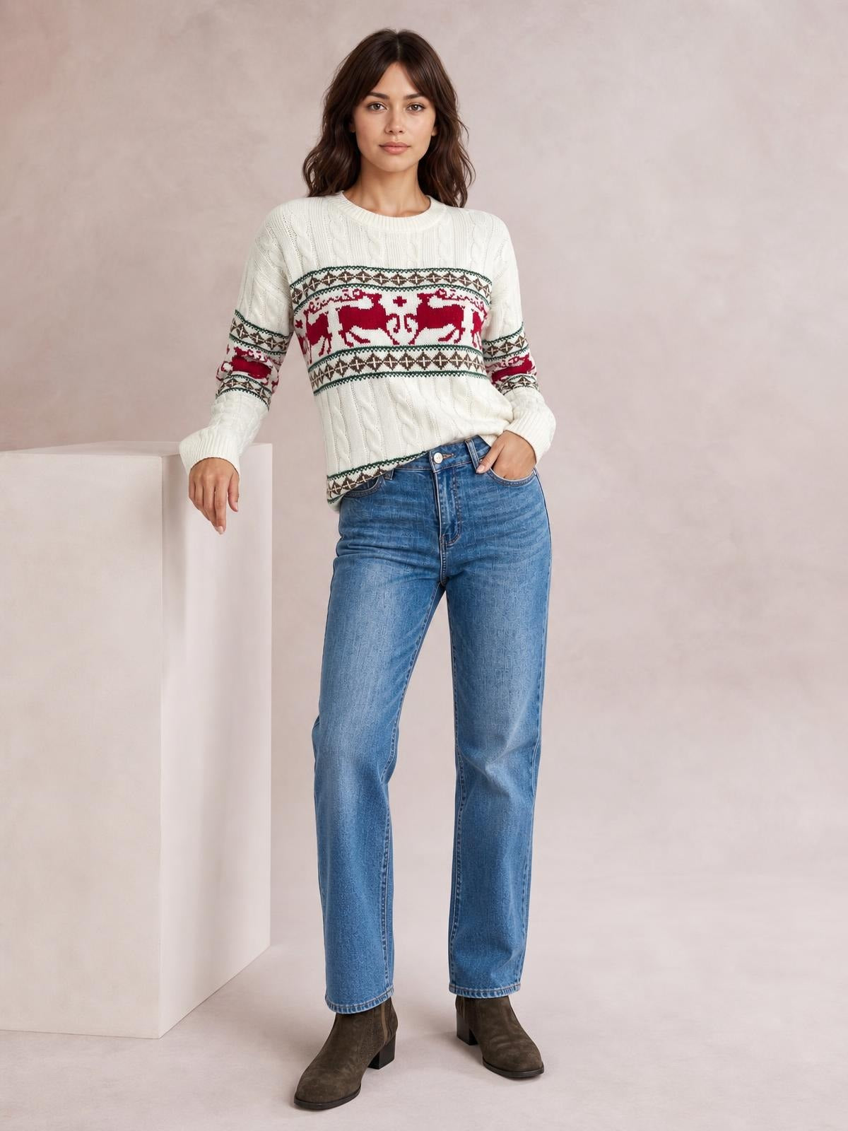 Model poses in a white cable-knit Christmas sweater with red reindeer pattern bands, ribbed crew neck and cuffs, and a relaxed straight silhouette.