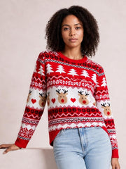 Model wears a red and white Christmas round neck sweater with long sleeves, reindeer and tree motifs, geometric bands, ribbed cuffs, and a relaxed silhouette.
