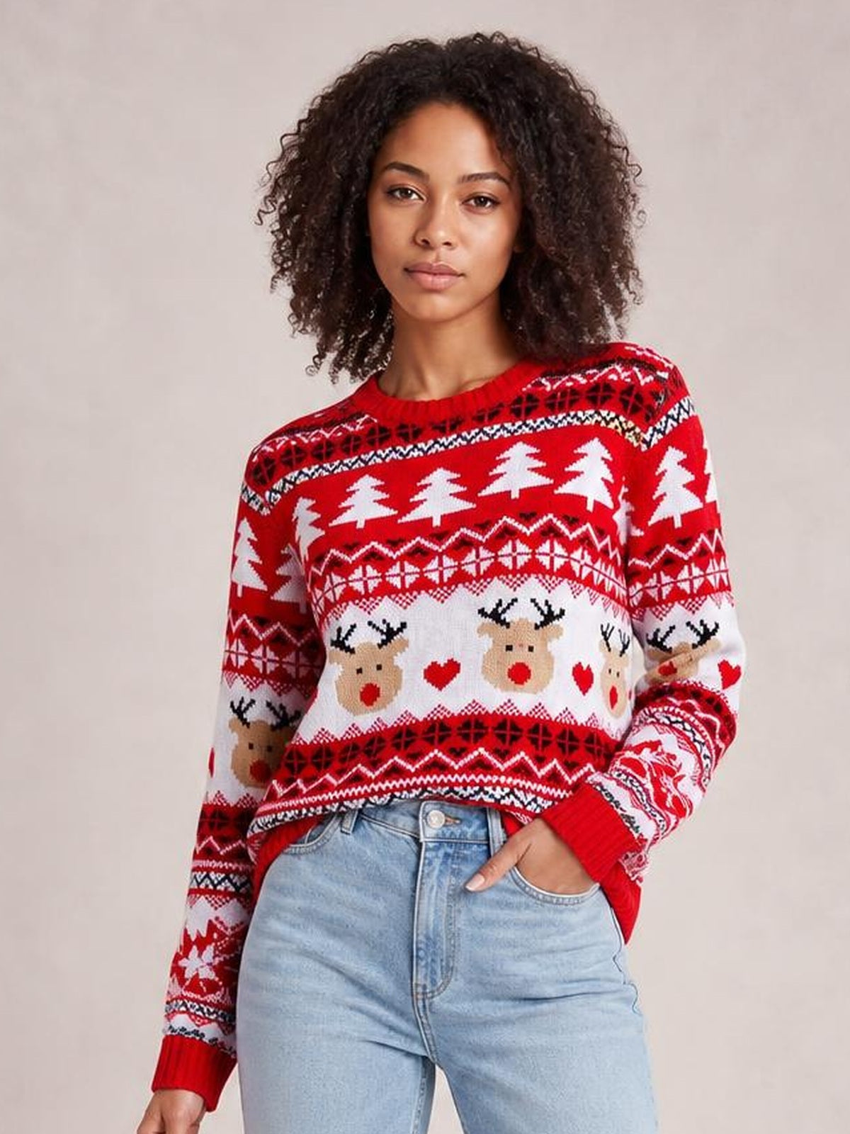 Model wearing a red and white Christmas round neck sweater with reindeer, tree, heart, and geometric patterns, ribbed cuffs, and a relaxed silhouette.