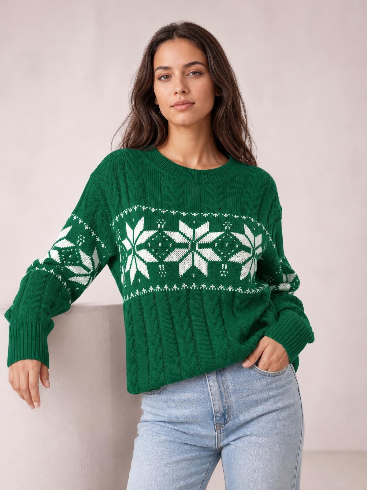 Woman posing in a green Christmas snowflake cable knit sweater with a relaxed silhouette, ribbed crew neckline, long sleeves, and white patterned detailing.