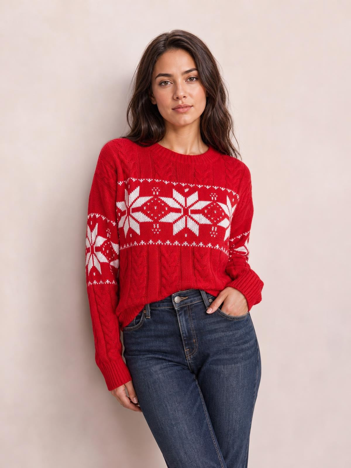 Model poses with one hand in her pocket wearing a red Christmas snowflake cable-knit sweater with long sleeves, ribbed trim, and a relaxed silhouette.