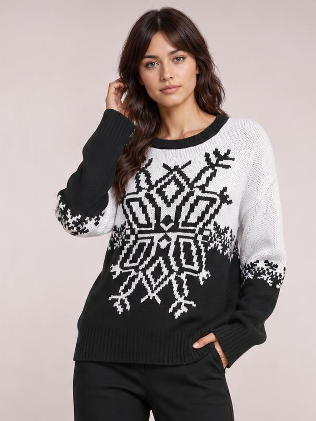 Model poses in a black and white Christmas snowflake sweater with a round neck, long sleeves, ribbed cuffs and hem, and relaxed silhouette.