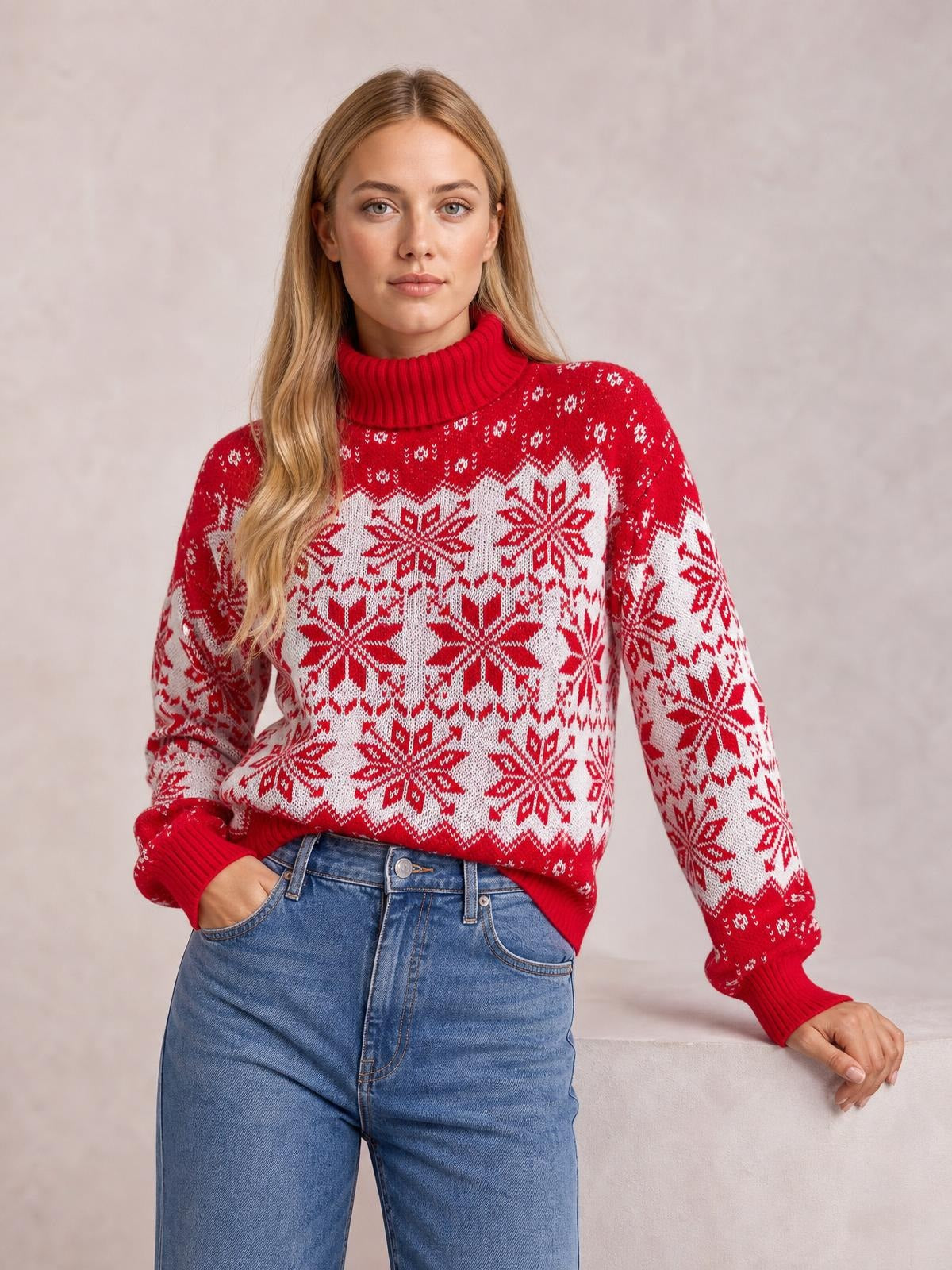 Model wearing a red Christmas snowflake turtleneck sweater with long sleeves, ribbed cuffs and collar, and a relaxed silhouette, posing with one hand in her jeans pocket.