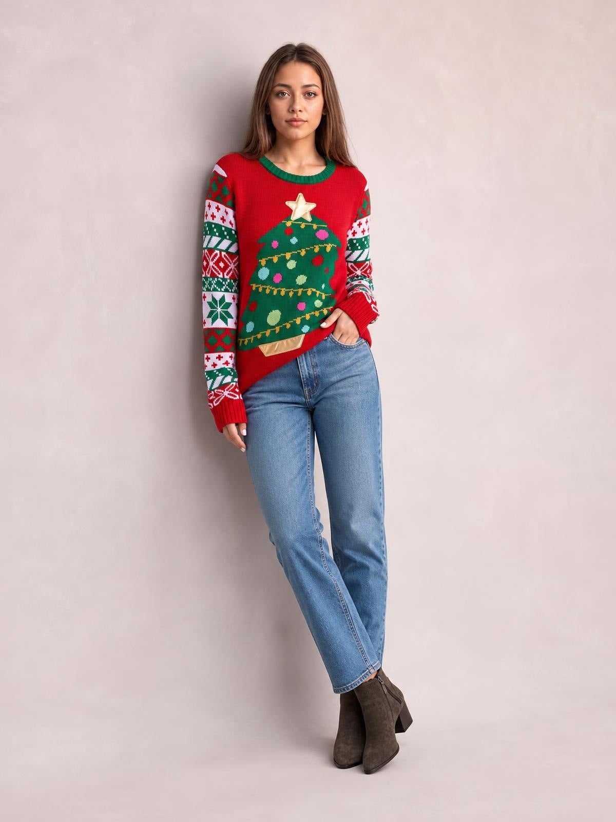 Model poses in a red Christmas tree graphic round neck sweater with green trim, patterned sleeves, ribbed cuffs, and a relaxed silhouette.