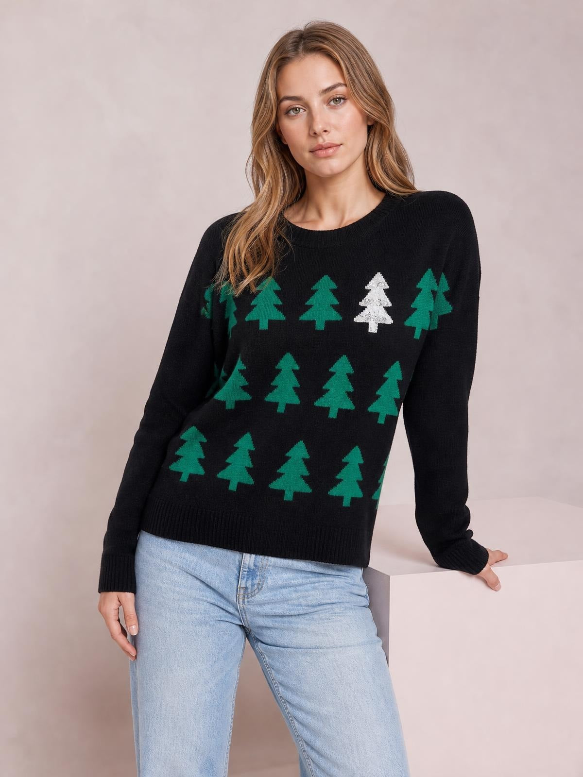 Model wearing a black Christmas tree sweater with green and white tree motifs, a round neck, long sleeves, ribbed trim, and a regular silhouette.
