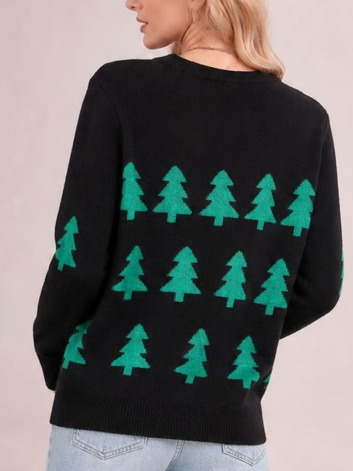 A model shows the back of a black Christmas tree sweater with green tree patterns, a round neck, long sleeves, and ribbed trim.