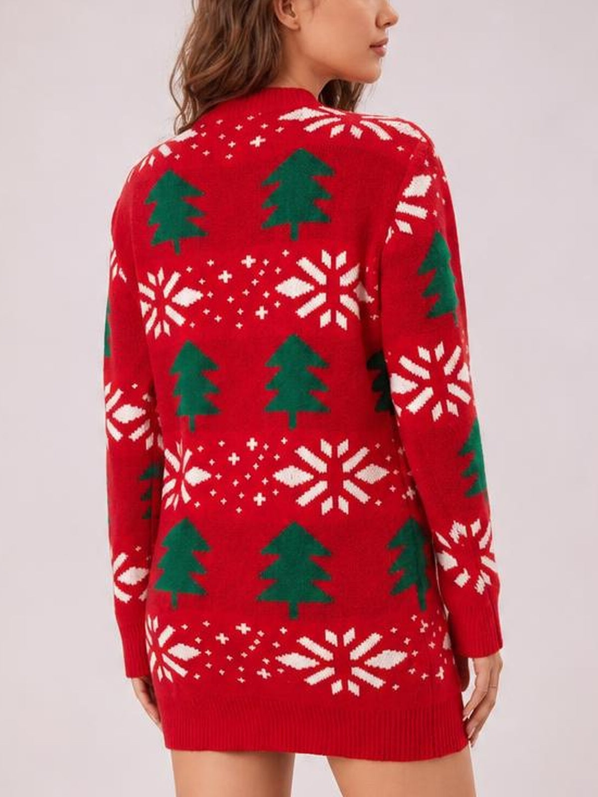 A model shows the back of a red Christmas tree round neck sweater dress with long sleeves, green tree and white snowflake patterns, and a relaxed silhouette.