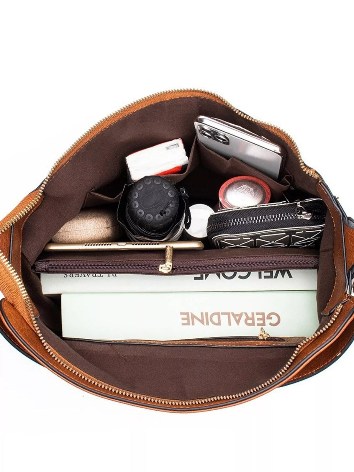 Open medium brown PU leather tote bag with a zip-top closure, spacious interior, multiple compartments, and several everyday items neatly stored inside.