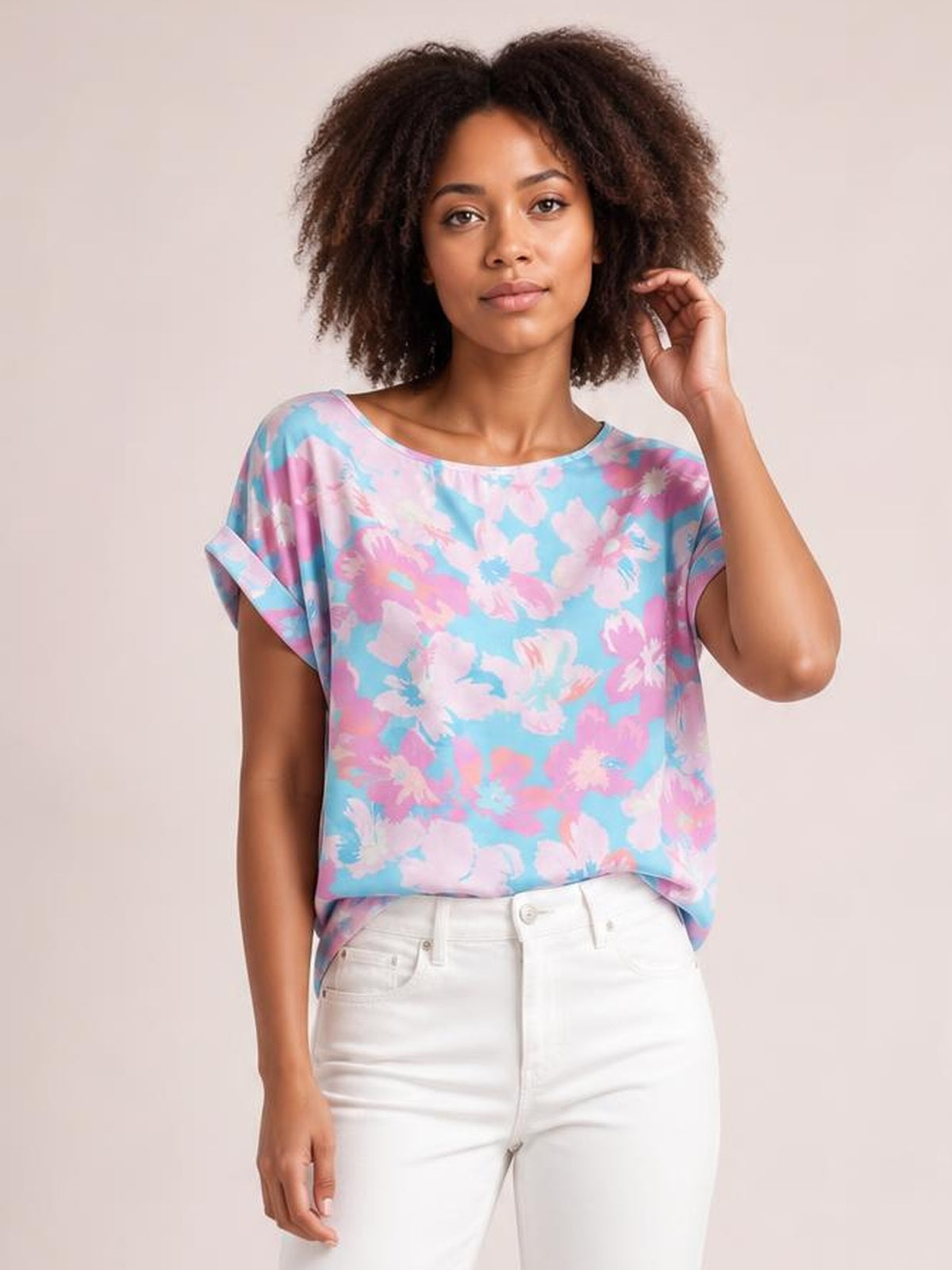 Model wearing a classic rolled sleeve T-shirt in blue and pink floral print, with a wide neckline, relaxed boxy silhouette, and cuffed short sleeves.