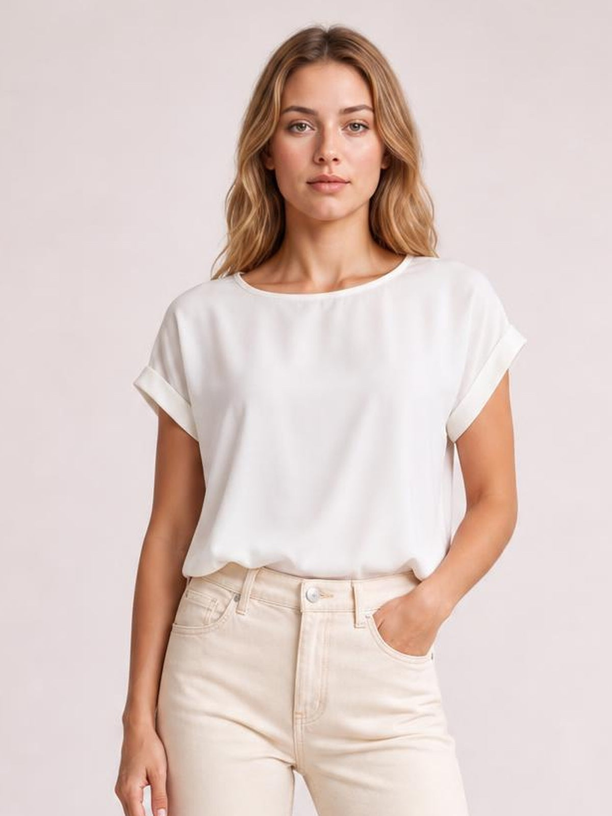 Model wearing a white classic rolled sleeve T-shirt with a relaxed straight silhouette and wide crew neckline, posing with one hand in her jeans pocket.