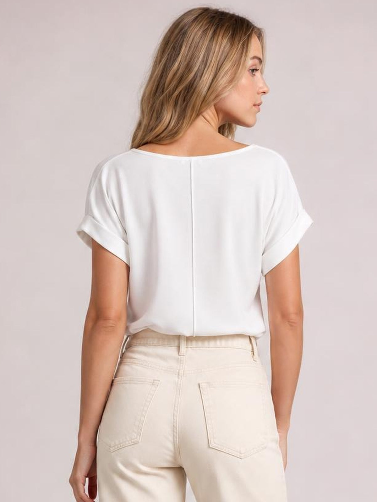 Model shown from behind wearing a white Classic Rolled Sleeve T-Shirt with a relaxed straight silhouette, round neckline, rolled cuffs, and center-back seam.
