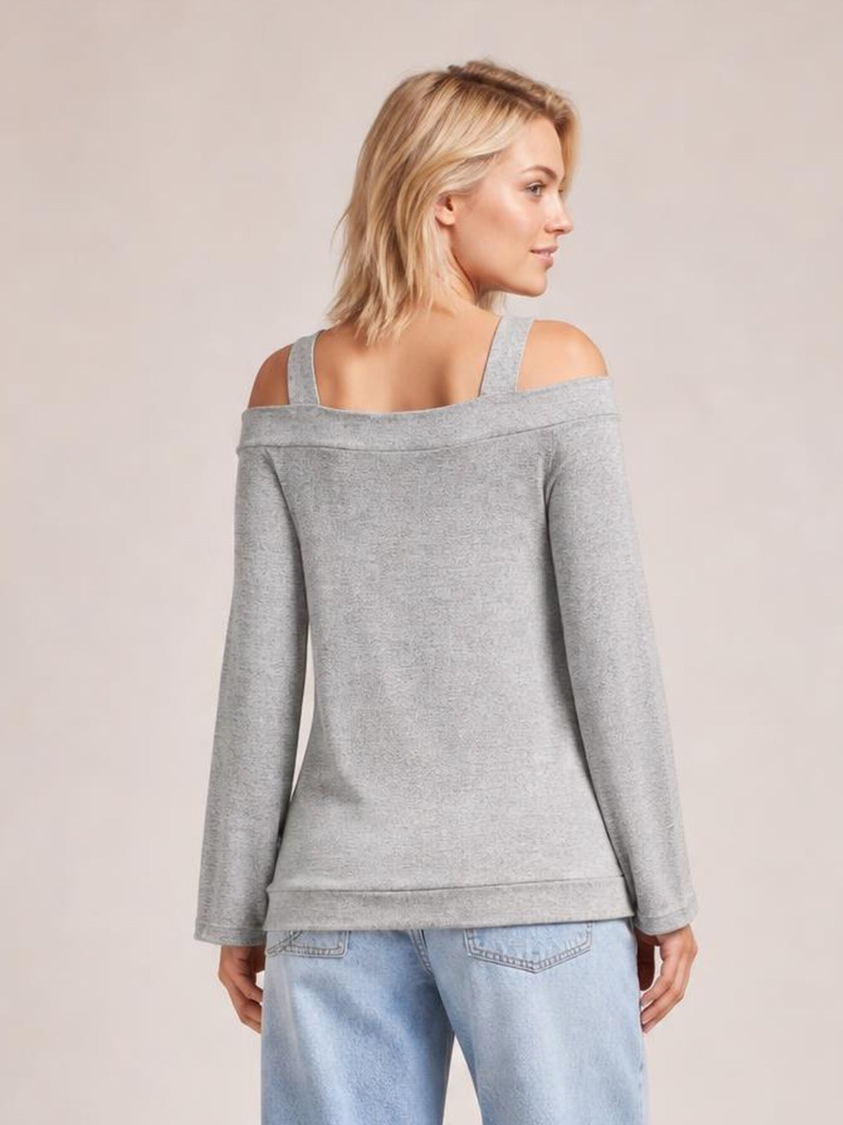 Model shown from the back in a gray cold shoulder cutout blouse with long sleeves, a relaxed straight silhouette, exposed shoulders, and a finished hem.