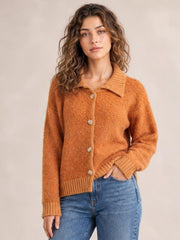 Model wearing a rust-orange collared neck button-down long sleeve cardigan with ribbed cuffs and hem, relaxed silhouette, and one hand in her jeans pocket.