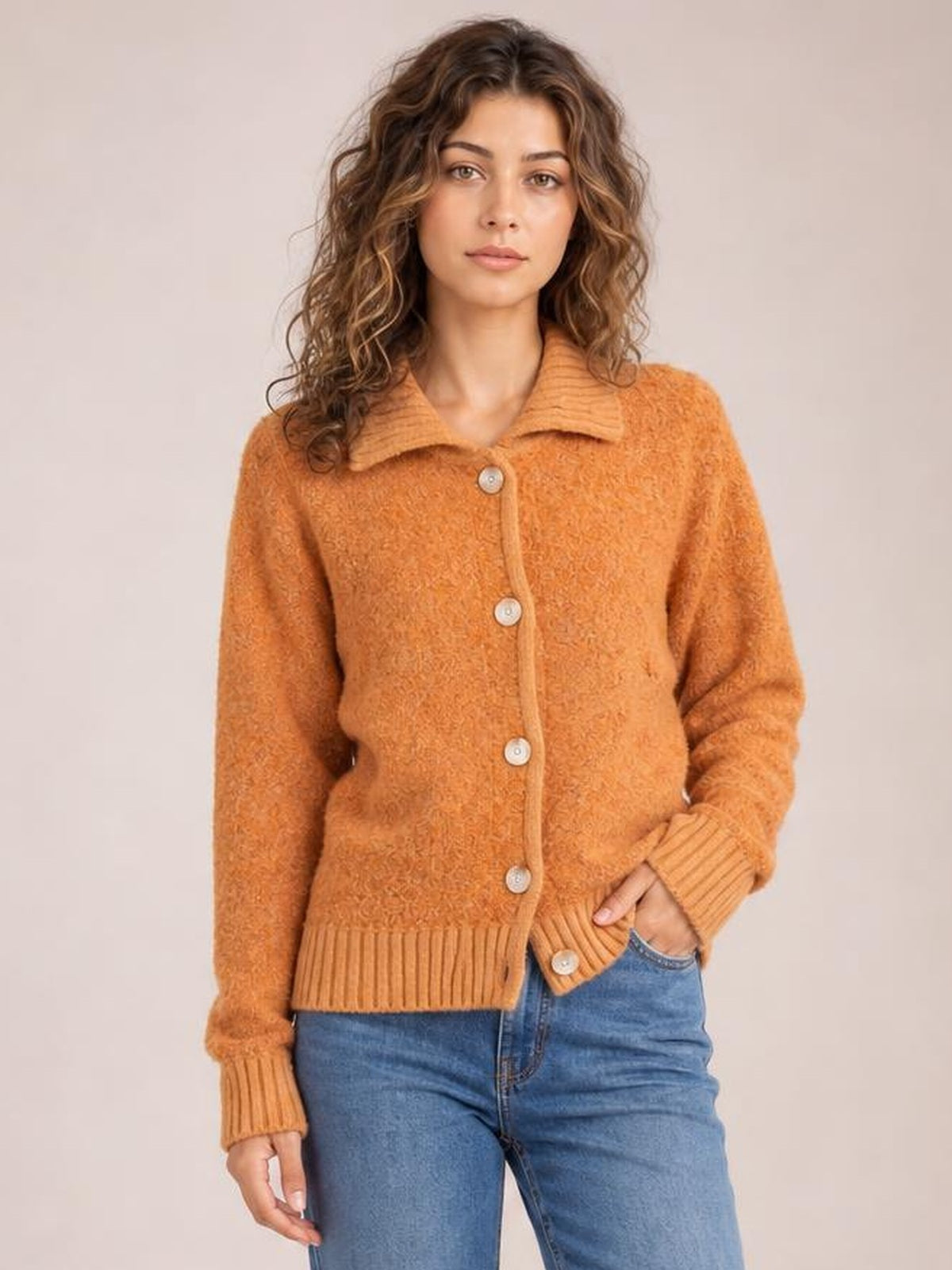 Model poses in a rust orange collared neck button-down cardigan with long sleeves, ribbed cuffs and hem, front buttons, and a relaxed silhouette.