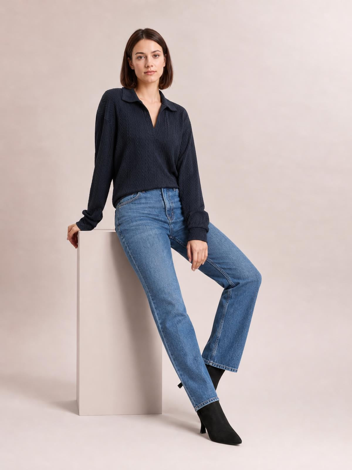 A model sits wearing a solid dark navy long-sleeve blouse with a Johnny collar, V-neck opening, textured knit construction, and a relaxed regular silhouette.