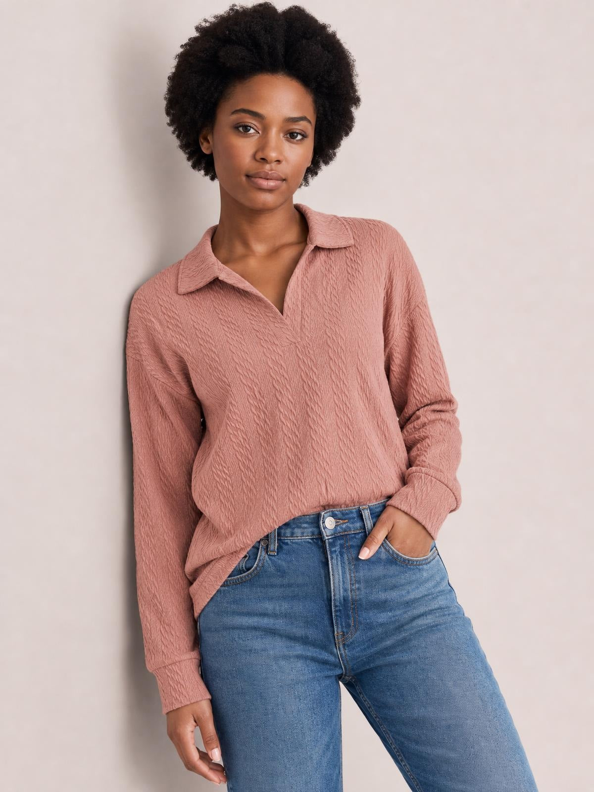 A model poses in a dusty rose long-sleeve blouse with a Johnny collar, subtle textured construction, relaxed regular silhouette, and cuffs, paired with jeans.
