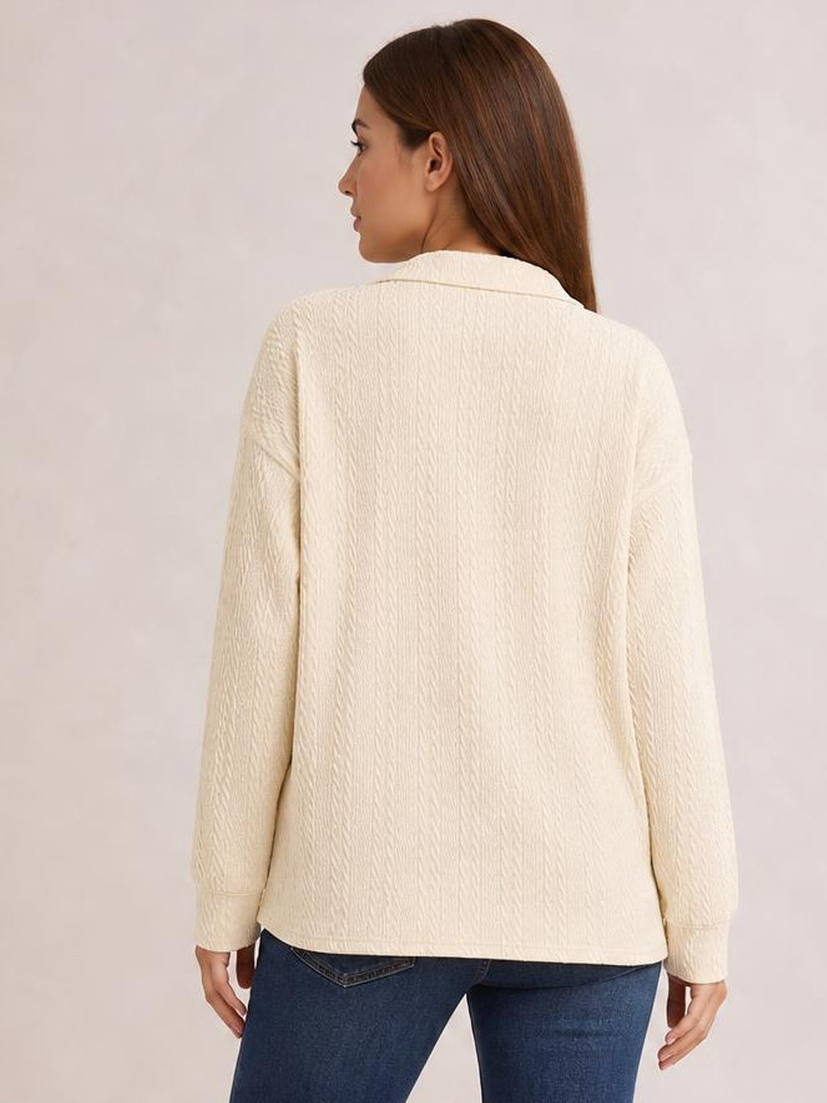 A model looks over her shoulder in a cream collared cable-knit blouse with long sleeves, textured construction, and a relaxed regular-length silhouette.