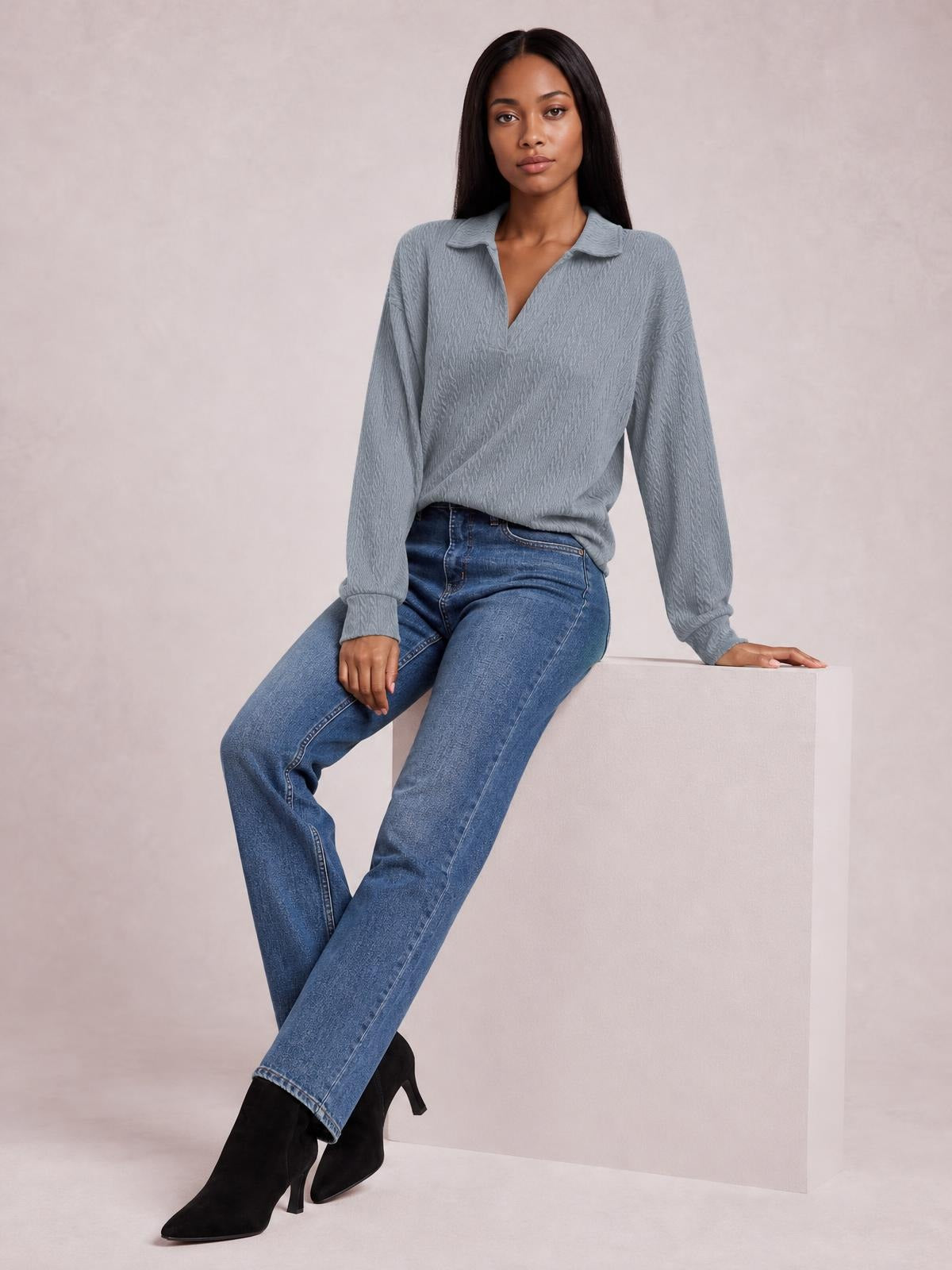 A seated model wears a solid gray cable-knit blouse with a Johnny collar, V opening, long sleeves, and a relaxed regular-length silhouette.