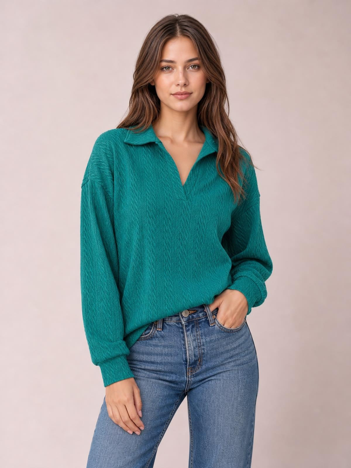 Model poses in a teal cable-knit blouse with a Johnny collar, V-neck opening, long sleeves, textured construction, and relaxed regular silhouette.